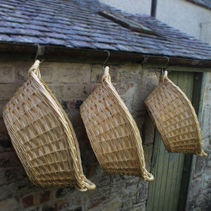 Freshly woven washing baskets hanging in old out building 